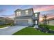 Charming two-story home with landscaped yard, gray siding, and a two-car garage at sunset at 8918 Waxwing Way, Parrish, FL 34219