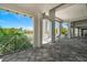 Expansive balcony featuring tile flooring, white pillars, and views of the pool and lush landscaping at 10165 Canaveral Cir, Sarasota, FL 34241