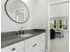Modern bathroom with a sleek vanity, round mirror, and a glimpse into the adjacent living space at 10165 Canaveral Cir, Sarasota, FL 34241