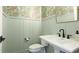Stylish powder room featuring green board and batten, floral wallpaper and a pedestal sink at 10165 Canaveral Cir, Sarasota, FL 34241