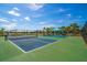 Well-maintained tennis courts with blue surfaces, surrounded by lush landscaping and shaded seating areas at 10165 Canaveral Cir, Sarasota, FL 34241