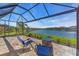 Spacious screened lanai with a beautiful lake view, stone fire pit, and comfortable lounge chairs at 10230 Highland Park Pl, Palmetto, FL 34221