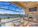 Outdoor living space featuring a screened lanai, an outdoor kitchen with grill, seating area, and scenic lake views at 10230 Highland Park Pl, Palmetto, FL 34221