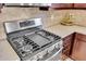 Close-up of a stainless steel gas range, complemented by granite countertops and a stylish backsplash in the kitchen at 10230 Highland Park Pl, Palmetto, FL 34221