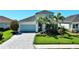 Charming single-Gathering home featuring a well-manicured lawn, mature palm trees, and a two-car garage at 10527 Falling Leaf Ct, Parrish, FL 34219