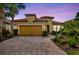 Charming single-Gathering home with lush landscaping and a brick-paved driveway at dusk at 12711 Del Corso Loop, Bradenton, FL 34211