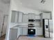 Well-lit kitchen featuring modern cabinets, stone countertops, stainless appliances, and an electric range at 1541 Music Ln, North Port, FL 34286