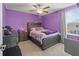 Cozy bedroom with purple accent wall, ceiling fan, and a large window at 1570 Ludington Ave, Wesley Chapel, FL 33543
