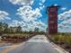 Community entrance featuring a wooden observation tower, bridge, and colorful landscaping at 1570 Ludington Ave, Wesley Chapel, FL 33543