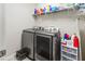 Modern laundry room featuring a stainless steel washer and dryer with storage at 1570 Ludington Ave, Wesley Chapel, FL 33543
