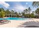 Community pool featuring a sun deck with lounge chairs and lush tropical landscaping at 1570 Ludington Ave, Wesley Chapel, FL 33543