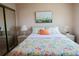 Bright bedroom with floral bedding, decorative painting and mirror closet doors, creating a cheerful, relaxing atmosphere at 1838 Sunny Dr # D35, Bradenton, FL 34207