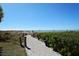 Sandy path leads to a serene beach with clear blue water, perfect for a relaxing day by the sea at 1935 Gulf Of Mexico Dr # G7-402, Longboat Key, FL 34228