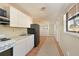 Galley kitchen with white cabinets and appliances opens to carpeted dining area at 2316 Bradford St, Sarasota, FL 34231