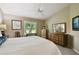 Bright bedroom with a ceiling fan, neutral walls, dresser, and shuttered windows at 2912 Fiddlers Bnd, Palmetto, FL 34221