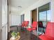 Enclosed balcony with tile floor features red chairs, side tables, and a view of the lake at 3821 Lake Bayshore Dr # H-507, Bradenton, FL 34205