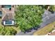 An aerial view of a cozy home next to an immense shady tree, with screened pool area and neat driveway at 3842 Glen Oaks Manor Dr, Sarasota, FL 34232