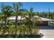 Inviting single-story home featuring a metal roof, a two-car garage, and lush tropical landscaping with palm trees at 401 73Rd St, Holmes Beach, FL 34217