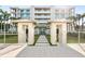 Beautiful building with manicured lawns, white tiled walkways, and beachy palm trees at 4765 Gulf Of Mexico Dr # B202, Longboat Key, FL 34228