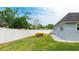 Spacious backyard with white vinyl fencing, boats on trailer, well-manicured lawn and a light-grey home exterior at 504 Whitfield Ave, Sarasota, FL 34243