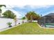 Expansive backyard with a well-kept lawn, complemented by vibrant flowers, a white fence, and screened in pool at 504 Whitfield Ave, Sarasota, FL 34243