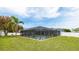 Lush backyard showcasing a sparkling pool, complemented by a screened enclosure, manicured landscaping, and mature trees at 504 Whitfield Ave, Sarasota, FL 34243