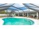 A turquoise pool reflecting the sky, with an adjacent patio featuring a BBQ, dining table, and lounge chairs near the house at 504 Whitfield Ave, Sarasota, FL 34243