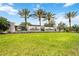 A manicured lawn and lush landscaping surround the community's stone entrance with palm trees on a partly cloudy day at 5313 Greenbrook Dr, Sarasota, FL 34238