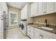 Spacious laundry room with abundant storage, a utility sink, modern washer, and dryer at 5313 Greenbrook Dr, Sarasota, FL 34238