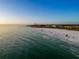 Expansive aerial view of a pristine white sand beach with clear turquoise waters and beachfront condos in the distance at 5512 Avenida Del Mare, Sarasota, FL 34242
