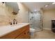 Bathroom featuring travertine floors, a wooden vanity, a modern glass shower, and a decorative mirror adding style at 5512 Avenida Del Mare, Sarasota, FL 34242