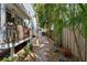 Landscaped walkway alongside home with a decorative wood fence featuring tropical foliage and vibrant red flowers at 5512 Avenida Del Mare, Sarasota, FL 34242