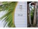 Well-lit house numbers on a white exterior wall, complemented by lush green palm trees at 5512 Avenida Del Mare, Sarasota, FL 34242