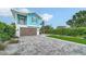 View of the property's paver driveway leading to a well-maintained two-story home with a wooden garage door at 5930 Briarwood Ave, Sarasota, FL 34231