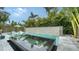 Backyard pool and spa surrounded by lush greenery and a unique stone wall, creating a private tropical retreat at 5930 Briarwood Ave, Sarasota, FL 34231