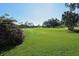 Scenic golf course view with lush green grass and mature trees under a clear blue sky at 626 Magellan Dr, Sarasota, FL 34243