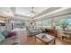 Bright living room with ceiling fan, wood floors, comfortable seating, and sliding glass doors to the lanai at 626 Magellan Dr, Sarasota, FL 34243