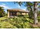 Backyard featuring a well-manicured lawn, mature trees, and a screened-in lanai area at 6492 Positano Ct, Sarasota, FL 34243