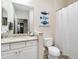 Bathroom featuring single vanity, toilet, shower with white curtain, and decorative fish wall art at 6492 Positano Ct, Sarasota, FL 34243