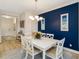 Dining area featuring a white table, chairs, chandelier, and a striking navy blue accent wall at 6492 Positano Ct, Sarasota, FL 34243