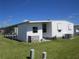Well-maintained single story mobile home exterior with a tidy lawn, carport, and traditional design at 705 Blackburn Blvd, North Port, FL 34287