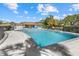 Community pool with a fence and a clubhouse, surrounded by trees and lounge chairs on a sunny day at 7205 Wood Creek Dr # 16, Sarasota, FL 34231