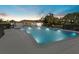 Illuminated community pool at dusk, surrounded by trees and with the clubhouse in the background at 7205 Wood Creek Dr # 16, Sarasota, FL 34231