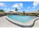Community pool surrounded by lush landscaping and multiple residential buildings under a blue sky with scattered clouds at 7205 Wood Creek Dr # 16, Sarasota, FL 34231