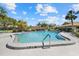 Community pool under a blue sky, surrounded by landscaping, residential buildings and a fence at 7205 Wood Creek Dr # 16, Sarasota, FL 34231