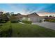 Charming home with manicured lawn, mature landscaping, and attached garages at dusk at 7205 Wood Creek Dr # 16, Sarasota, FL 34231
