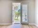 Open patio doors with views of tropical palms, green grass and white metal railing for outdoor living at 7810 34Th W Ave # 103, Bradenton, FL 34209