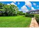 Lush green backyard with a large lawn, manicured landscaping, and a screened lanai at 8449 Lone Eagle Way, Sarasota, FL 34241