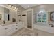 Bright bathroom featuring dual sinks, white cabinetry, soaking tub, and a glass enclosed walk-in shower at 8449 Lone Eagle Way, Sarasota, FL 34241