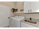 Convenient laundry room featuring white washer, dryer, sink and cabinet storage at 8449 Lone Eagle Way, Sarasota, FL 34241